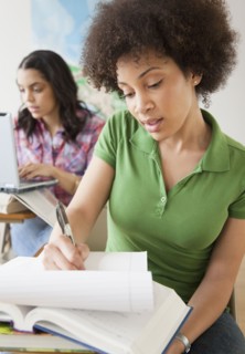 Mixed race woman taking notes in college classroom