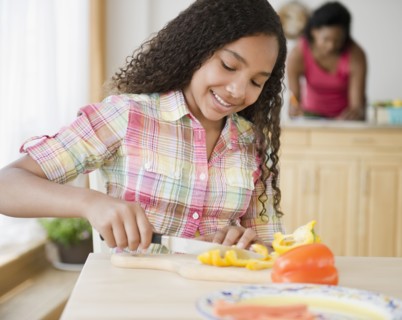 Mixed race girl cutting bell peppers