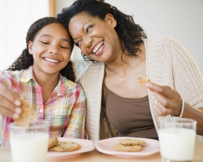 Mother and daughter eating cookies and milk together