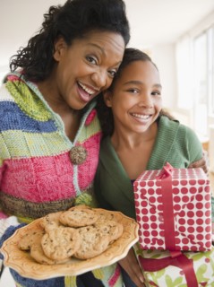 Mother and daughter carrying birthday gift and cookies