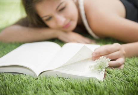 Indian woman laying in grass reading book
