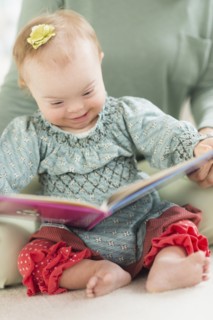Caucasian baby girl with Down Syndrome reading
