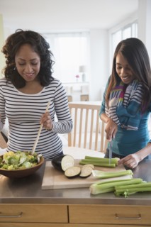 Mother and daughter chopping vegetables for salad