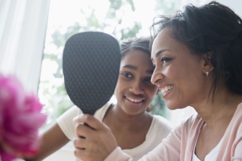 Mother and daughter looking in handheld mirror