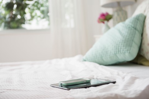 Cell phone and digital tablet on bed
