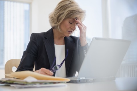 Caucasian businesswoman with headache using laptop