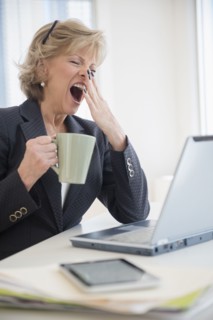 Fatigued Caucasian businesswoman drinking coffee and yawning