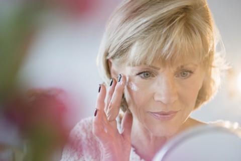 Older Caucasian woman applying moisturizer to face