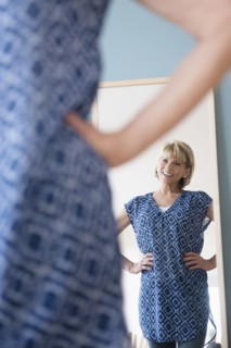 Older Caucasian woman admiring dress in mirror