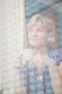 Older Caucasian woman drinking coffee at window
