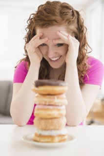 Caucasian woman resisting pile of donuts on plate