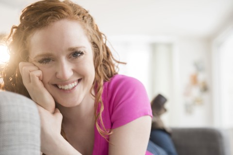 Smiling Caucasian woman laying on sofa