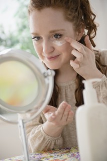Caucasian woman applying moisturizer to face