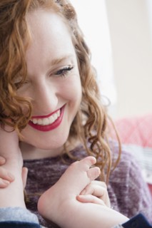 Caucasian woman holding foot of baby son