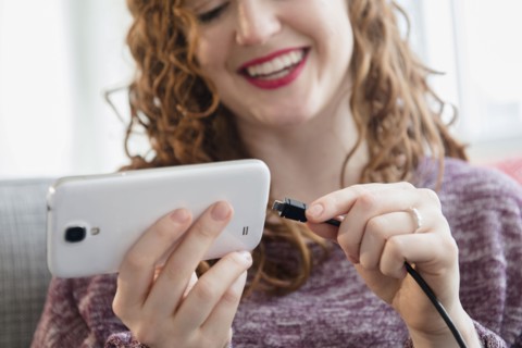 Caucasian woman connecting cord to cell phone