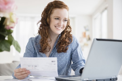 Caucasian woman paying bills using laptop