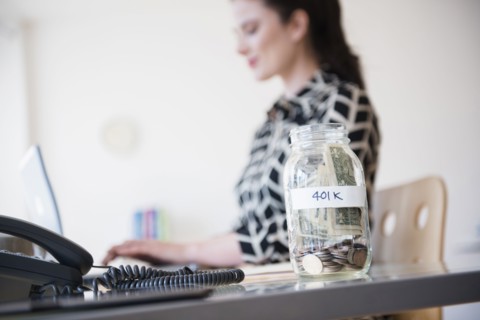 401k money jar on desk of Caucasian businesswoman