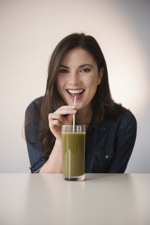 Caucasian woman drinking green smoothie with straw