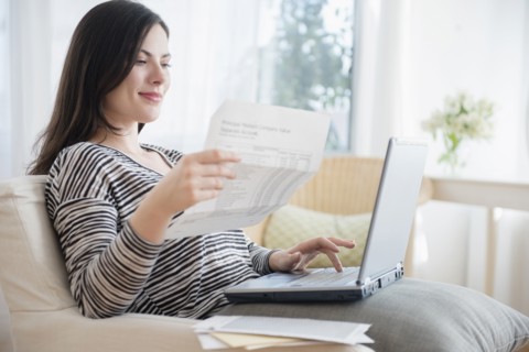 Caucasian woman paying bills using laptop