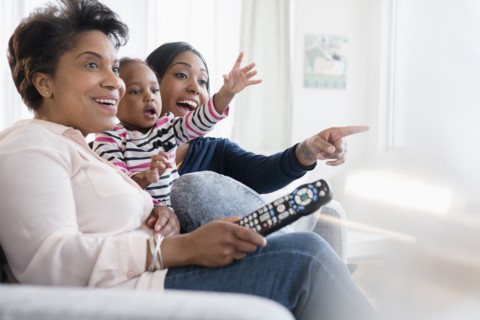 Black multi-generation family watching exciting television