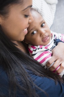 Black mother cuddling baby daughter