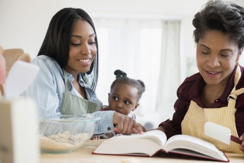 Black multi-generation family reading recipe in cookbook