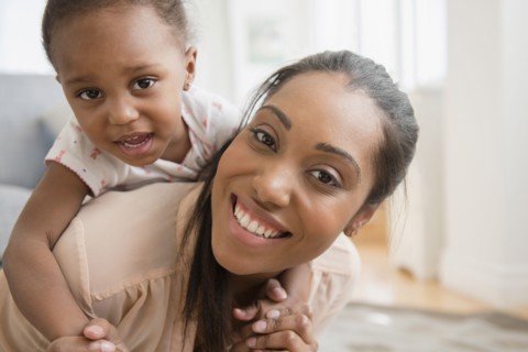 Black mother carrying baby daughter piggyback