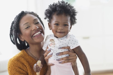 Smiling Black mother holding baby daughter