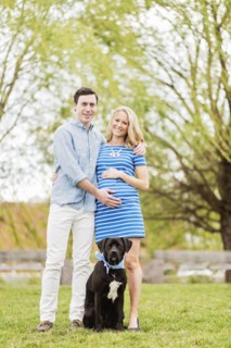 Smiling Caucasian man and expectant mother posing with dog in park