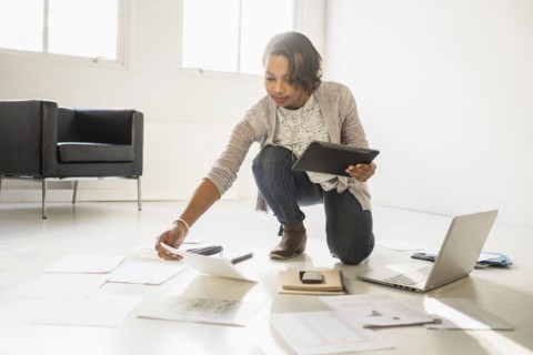 Black businesswoman using laptop and digital tablet on floor