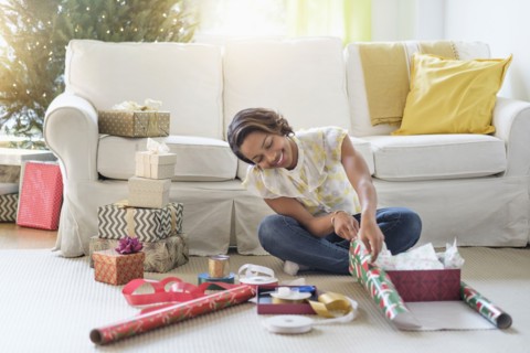 Black woman sitting on floor wrapping gifts