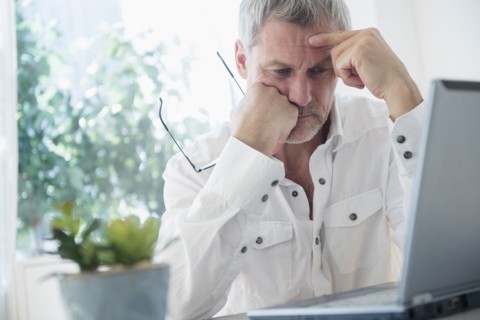 Frustrated older Caucasian man using laptop