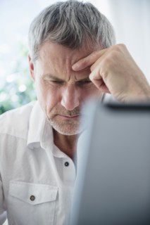 Frustrated older Caucasian man using laptop