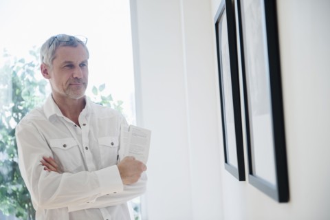 Older Caucasian man admiring artwork in gallery