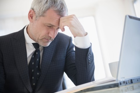 Frustrated older Caucasian businessman using laptop