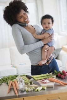 Mother talking on telephone while holding baby son in kitchen