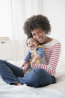 Smiling mother holding baby son on bed