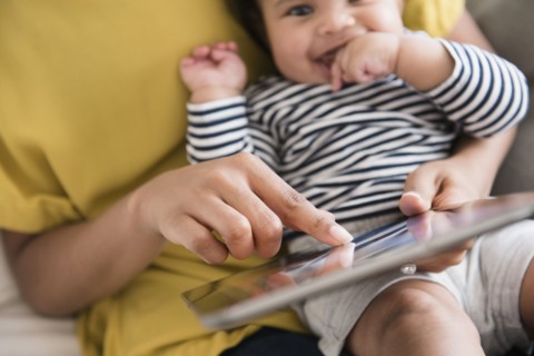 Mother holding baby son using digital tablet