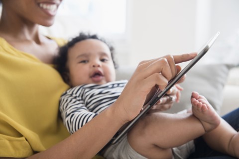 Mother holding baby son using digital tablet