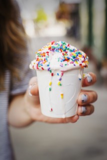 Caucasian woman holding cup of melting ice cream with sprinkles