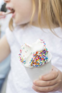Caucasian girl eating cup of ice cream with sprinkles