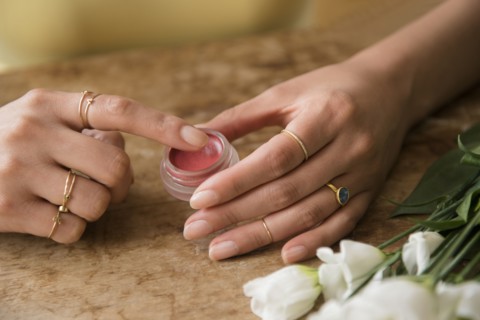 Hands of Hispanic woman holding jar of lip gloss