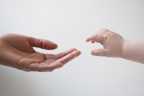 Hand of mother reaching for hand of baby son