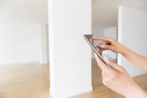 Hands of Hispanic woman using digital tablet in empty apartment