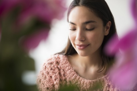 Pensive Hispanic woman behind pink flowers