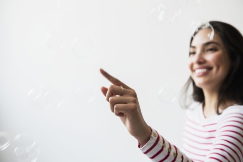 Hispanic woman popping floating bubbles