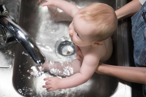 Mother bathing Caucasian baby son in sink