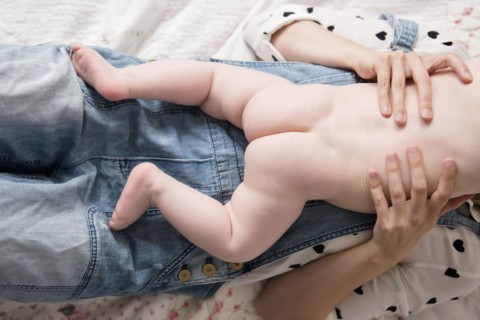 Caucasian mother laying on bed holding naked baby son