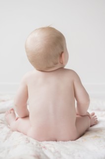 Naked Caucasian baby boy sitting on blanket