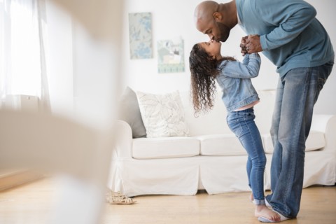 Daughter standing on feet of father and dancing
